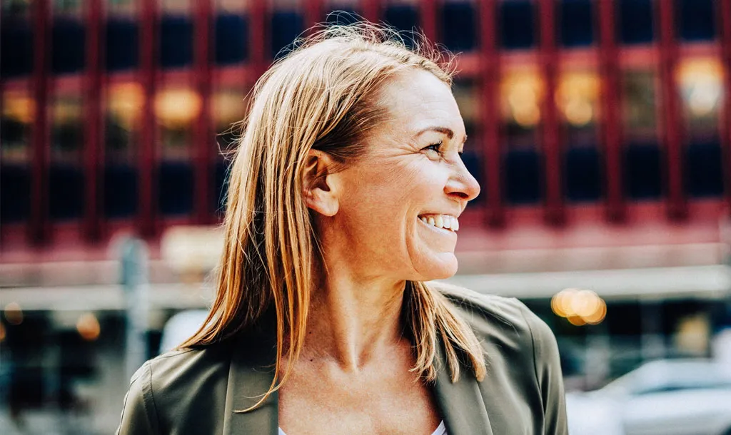 A woman looking to her left and smiling on a sunny day