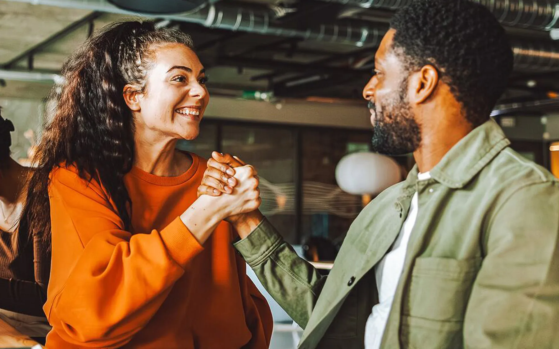 A man and woman shake hands and smile