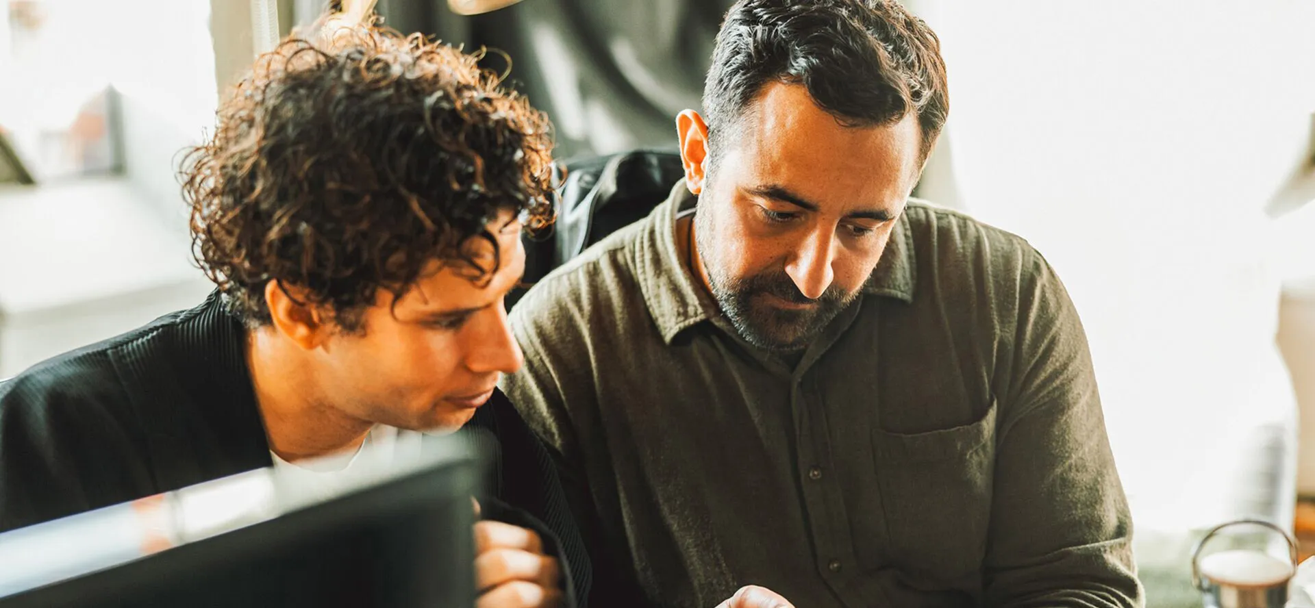 Two men sit at the same desk analyzing some work