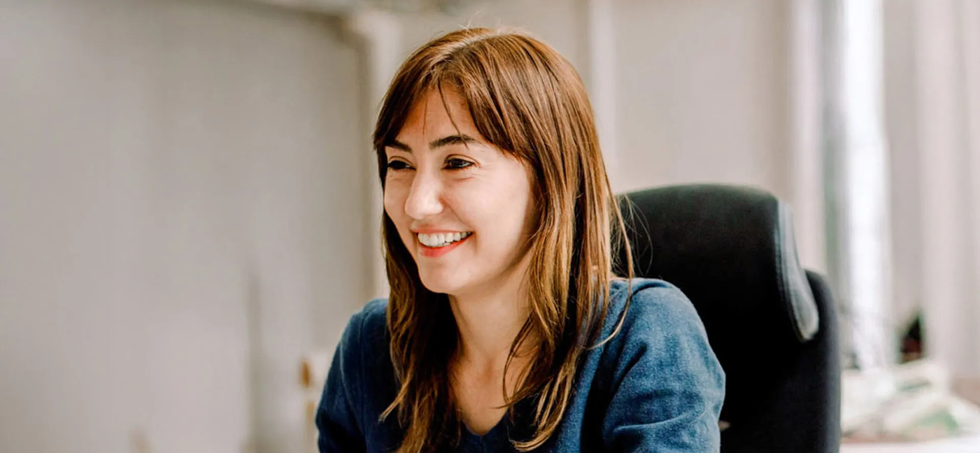 A woman wearing blue sitting at an office chair