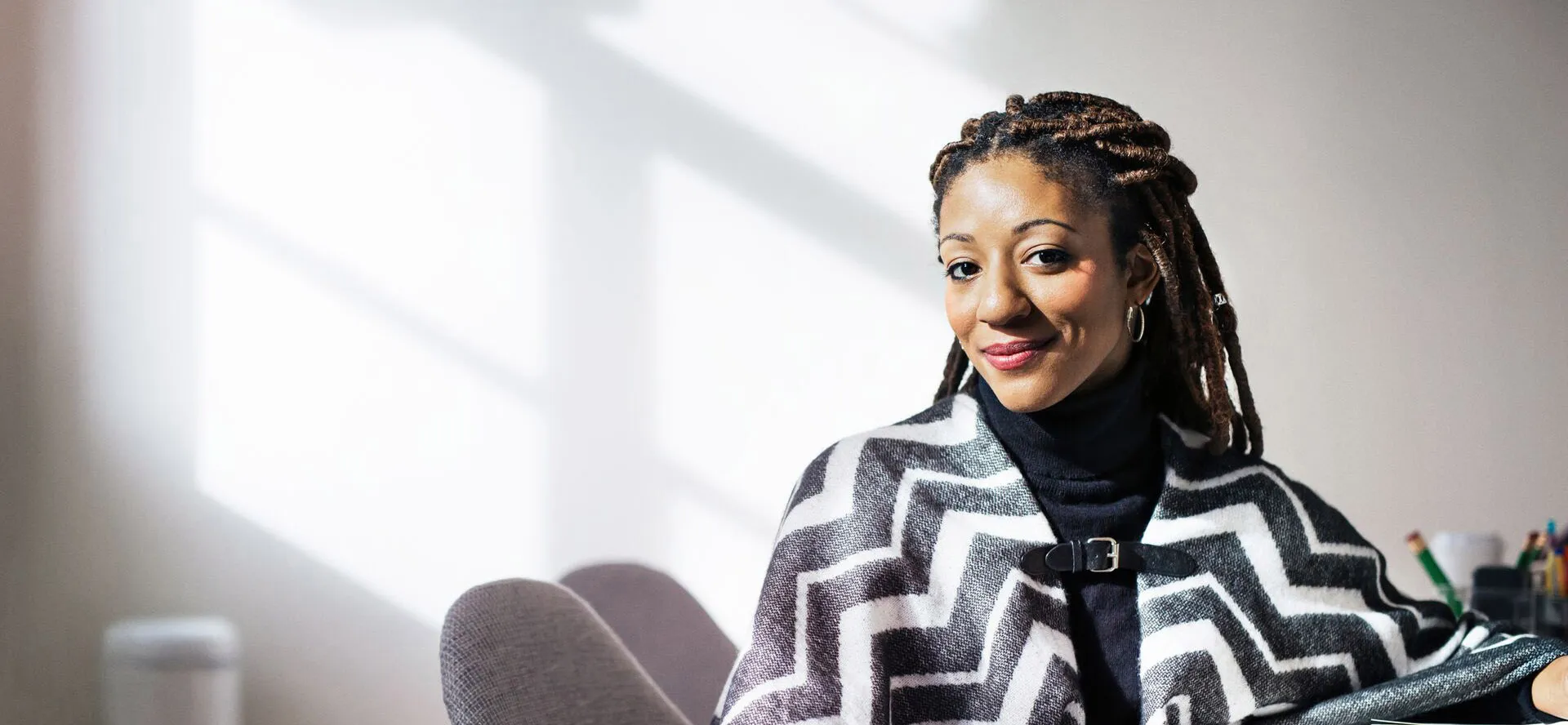 A black woman with braids smiling as she looks ahead