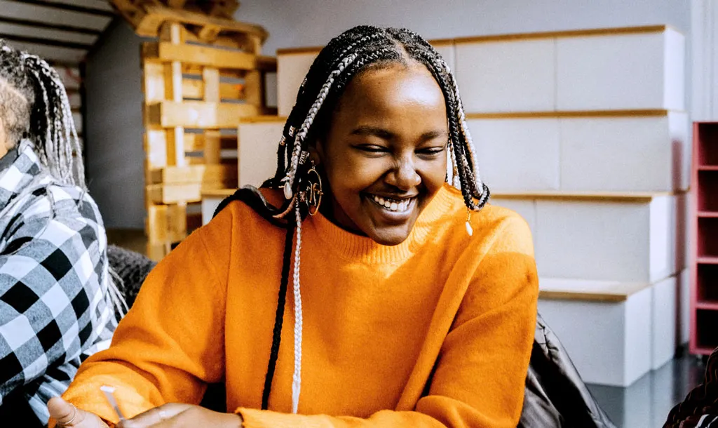 A young woman with braided hair smiling at her desk