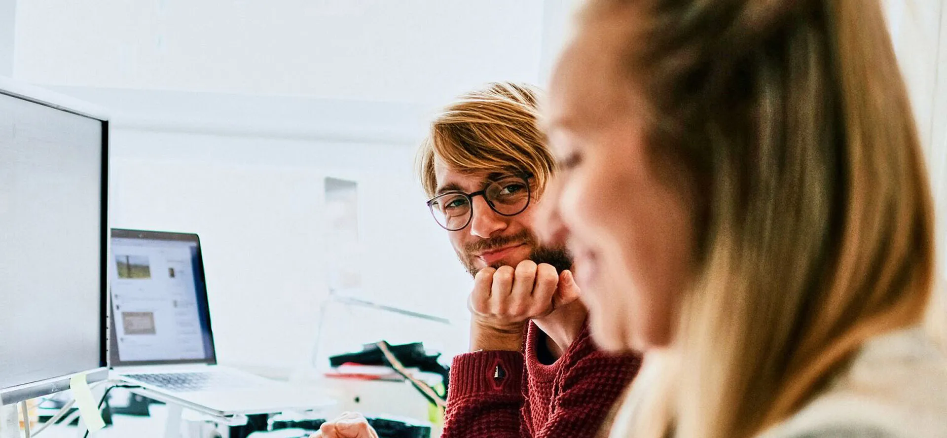 A man with glasses smiling across at a colleague