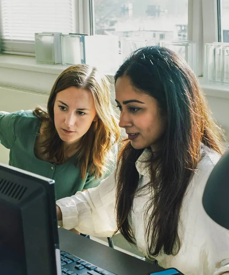 Two people smiling holding a laptop and phone