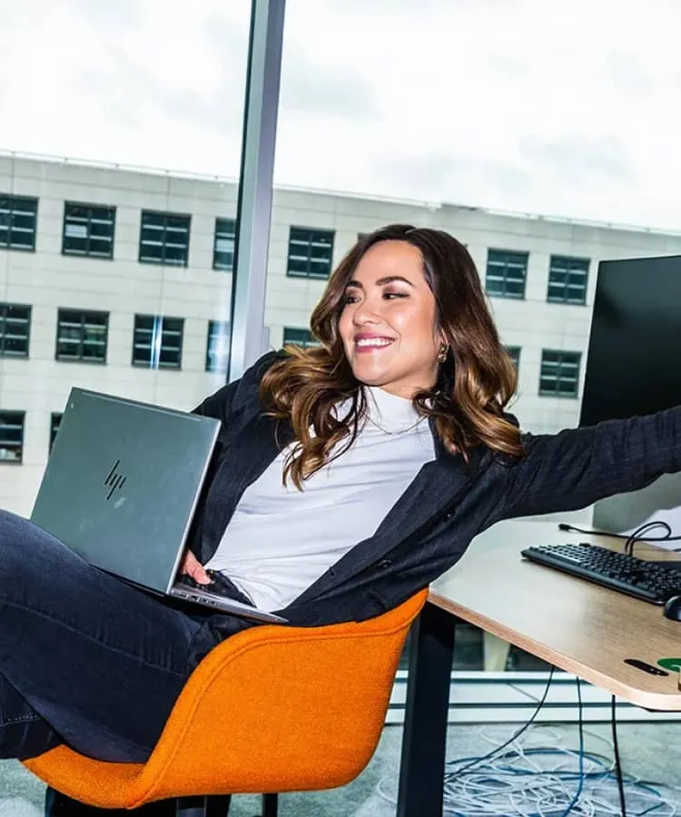 Woman leaning back on a chair using her laptop and smiling
