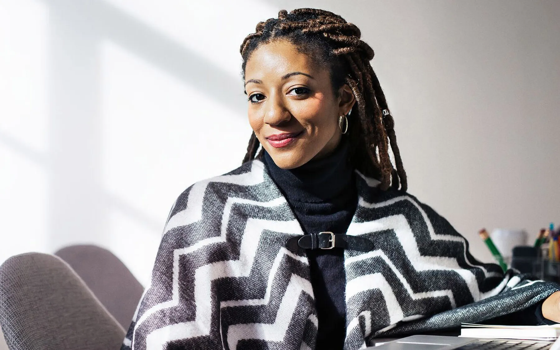 A black woman with braids smiling as she looks ahead