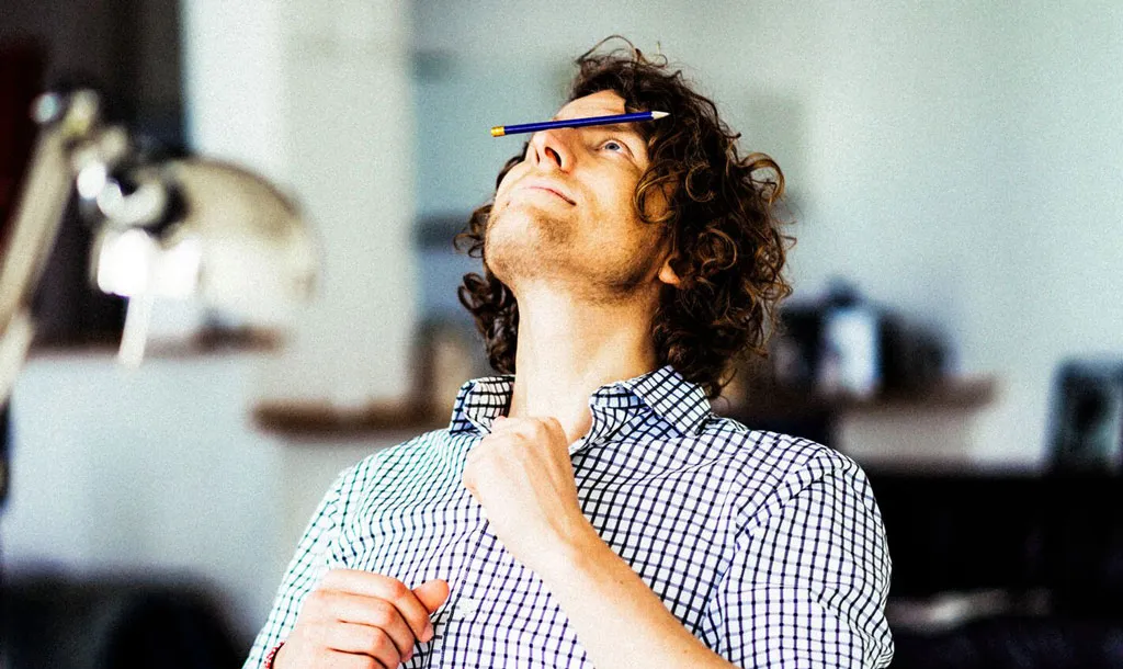A young man balancing a pencil on his nose