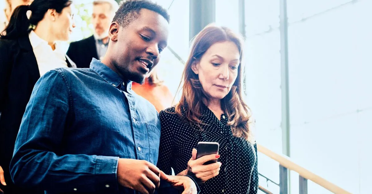 A black man and white woman in discussion walking down stairs