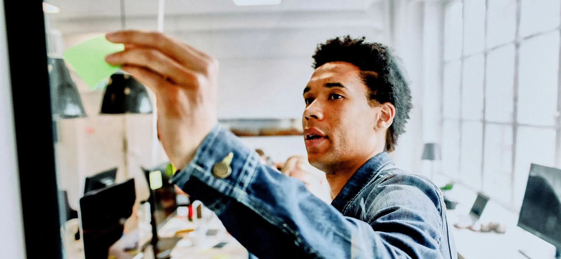 A man in a denim jacket taking something from a shelf
