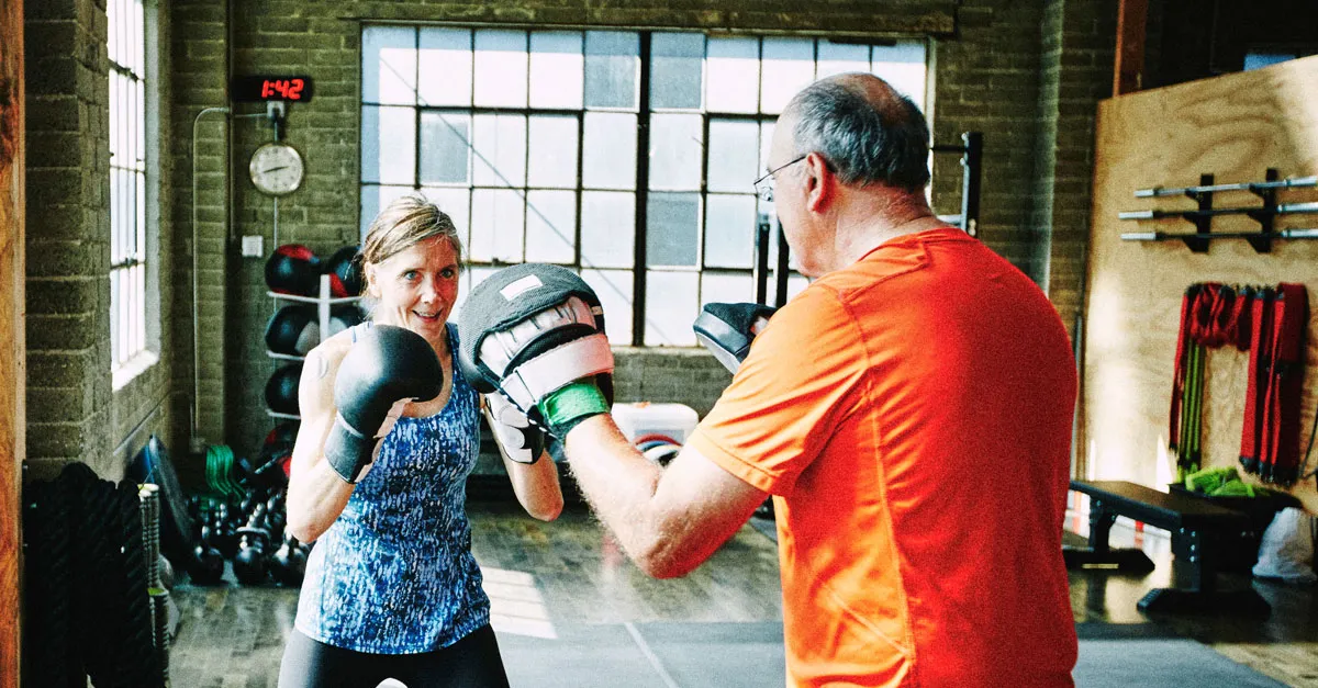 Older man and woman doing boxing drills in a gym