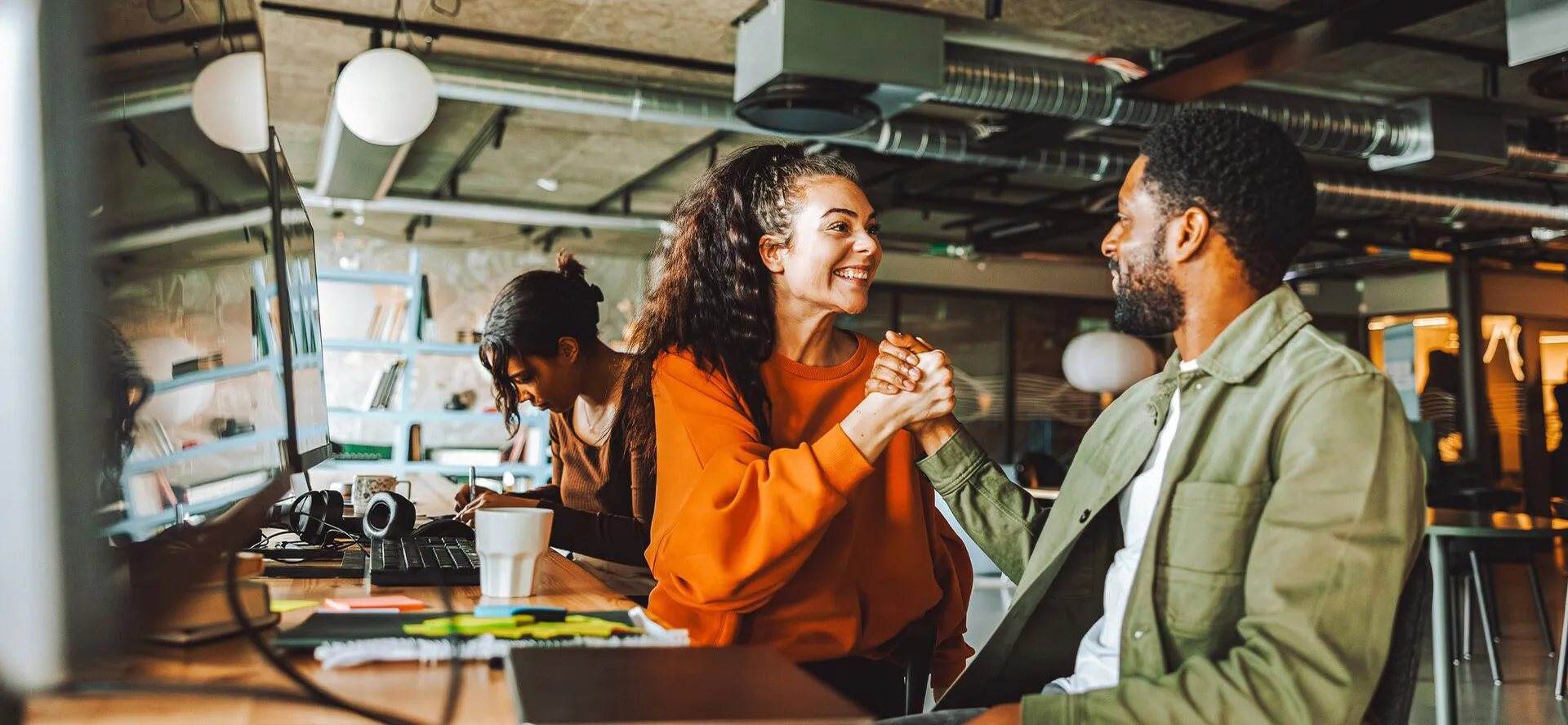 A man and woman shake hands and smile