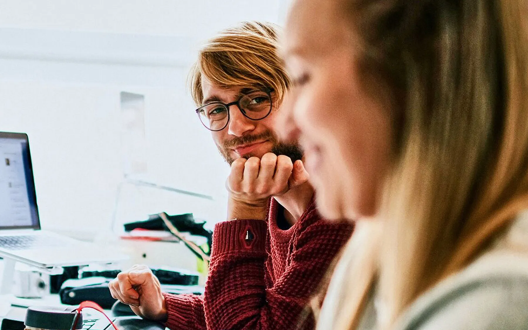 A man with glasses smiling across at a colleague