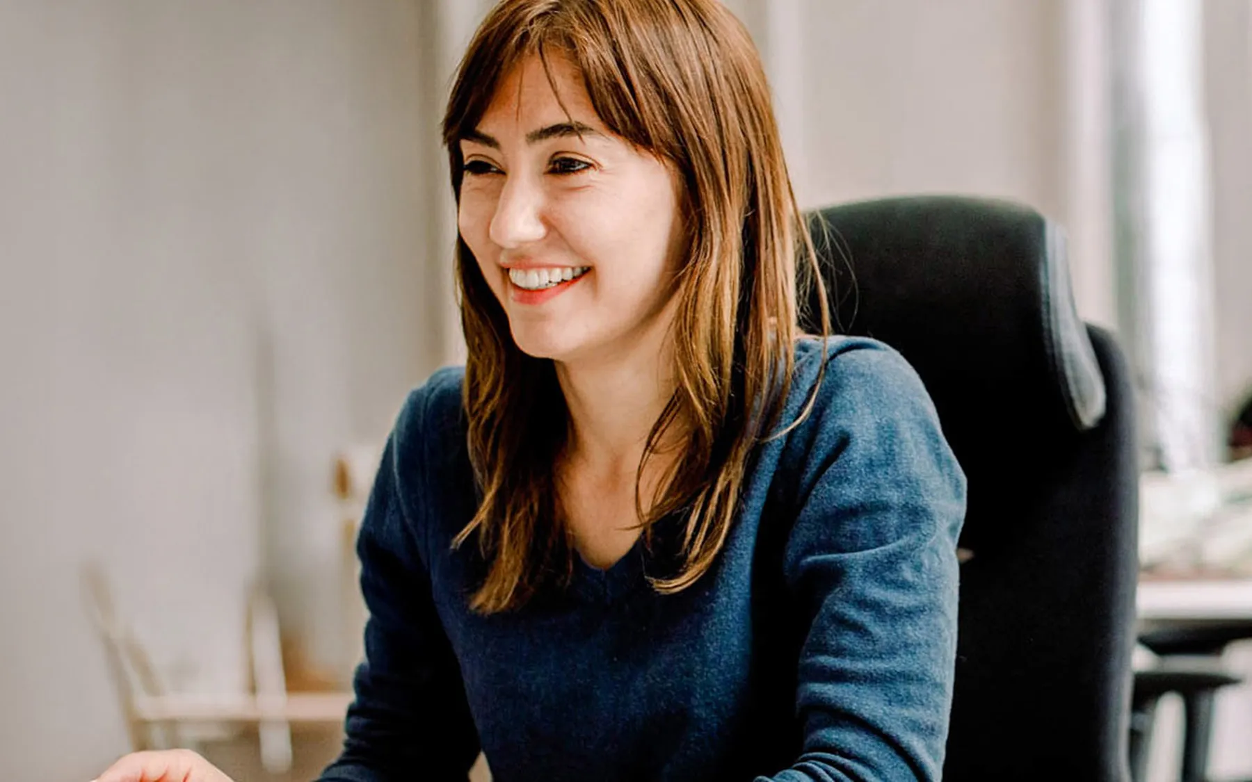 A woman wearing blue sitting at an office chair