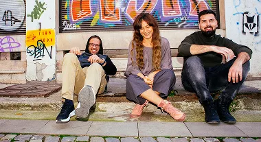 Three people sitting on the pavement.