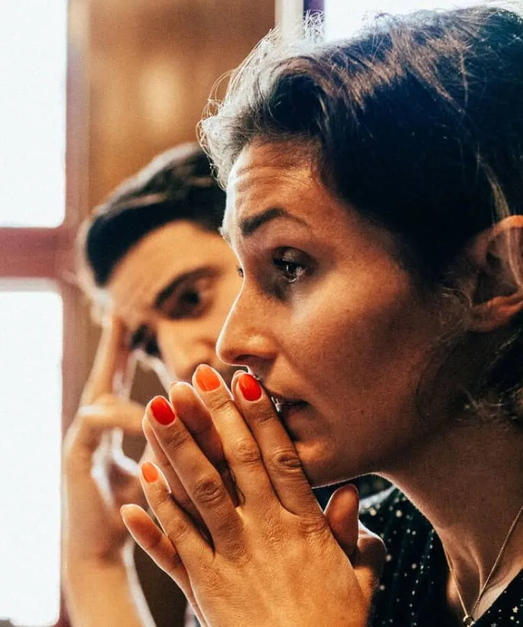 A woman with hands clasped together, working at her desk