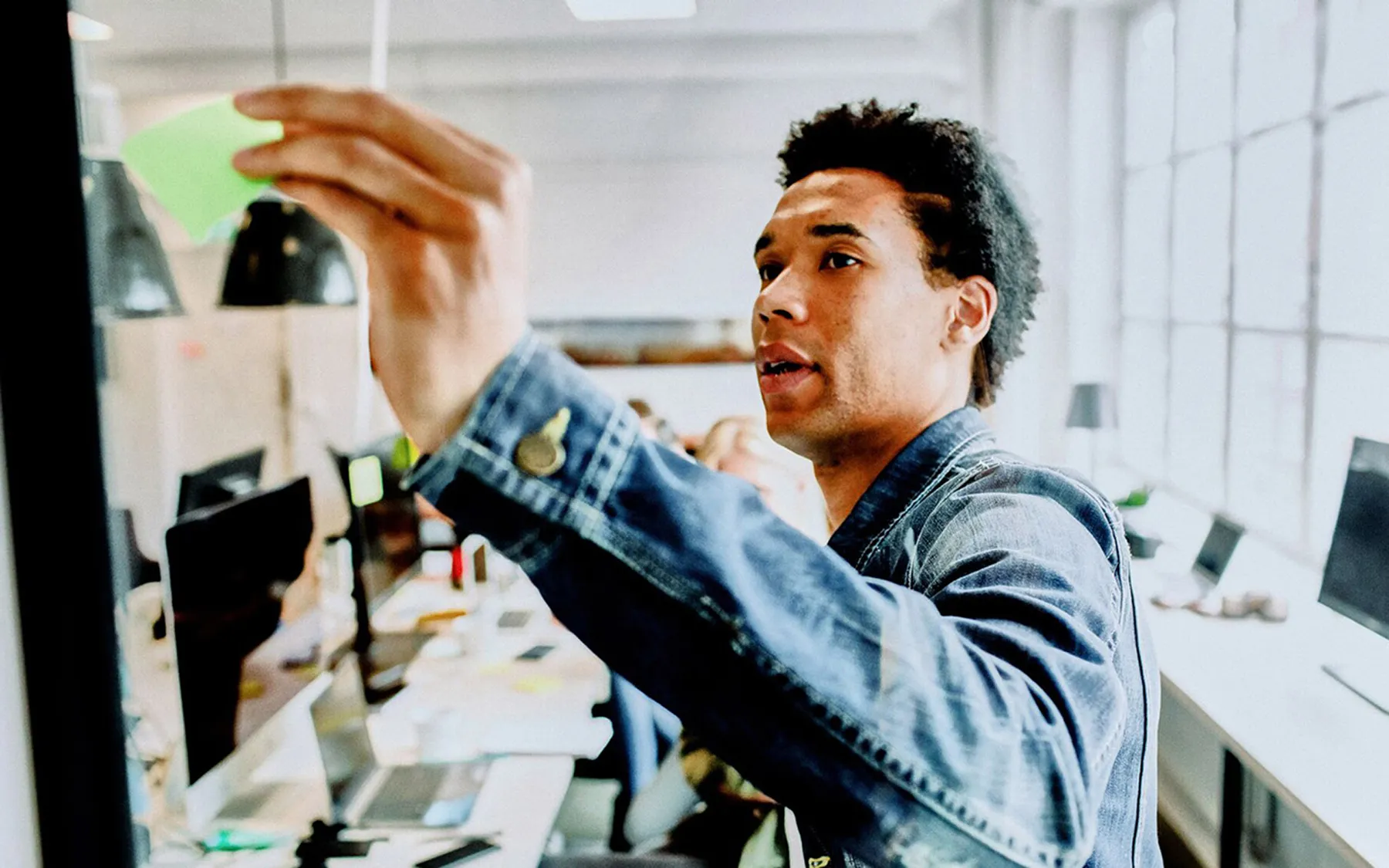A man in a denim jacket taking something from a shelf