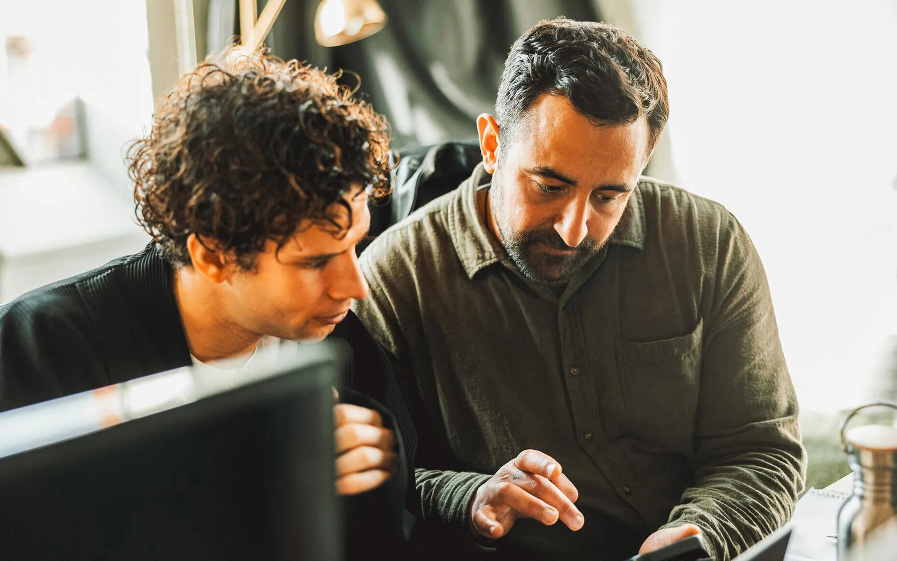 Two men sit at the same desk analyzing some work