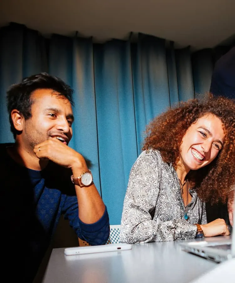 Two people smiling as they look at a laptop screen