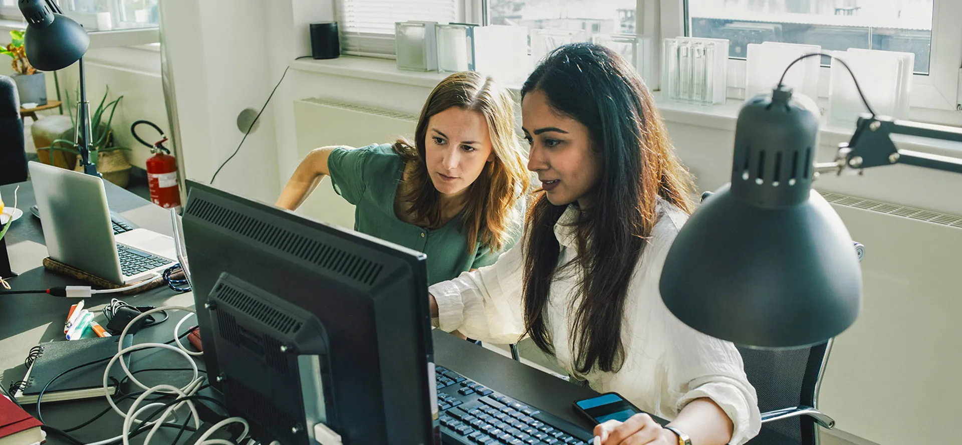 Two people smiling holding a laptop and phone