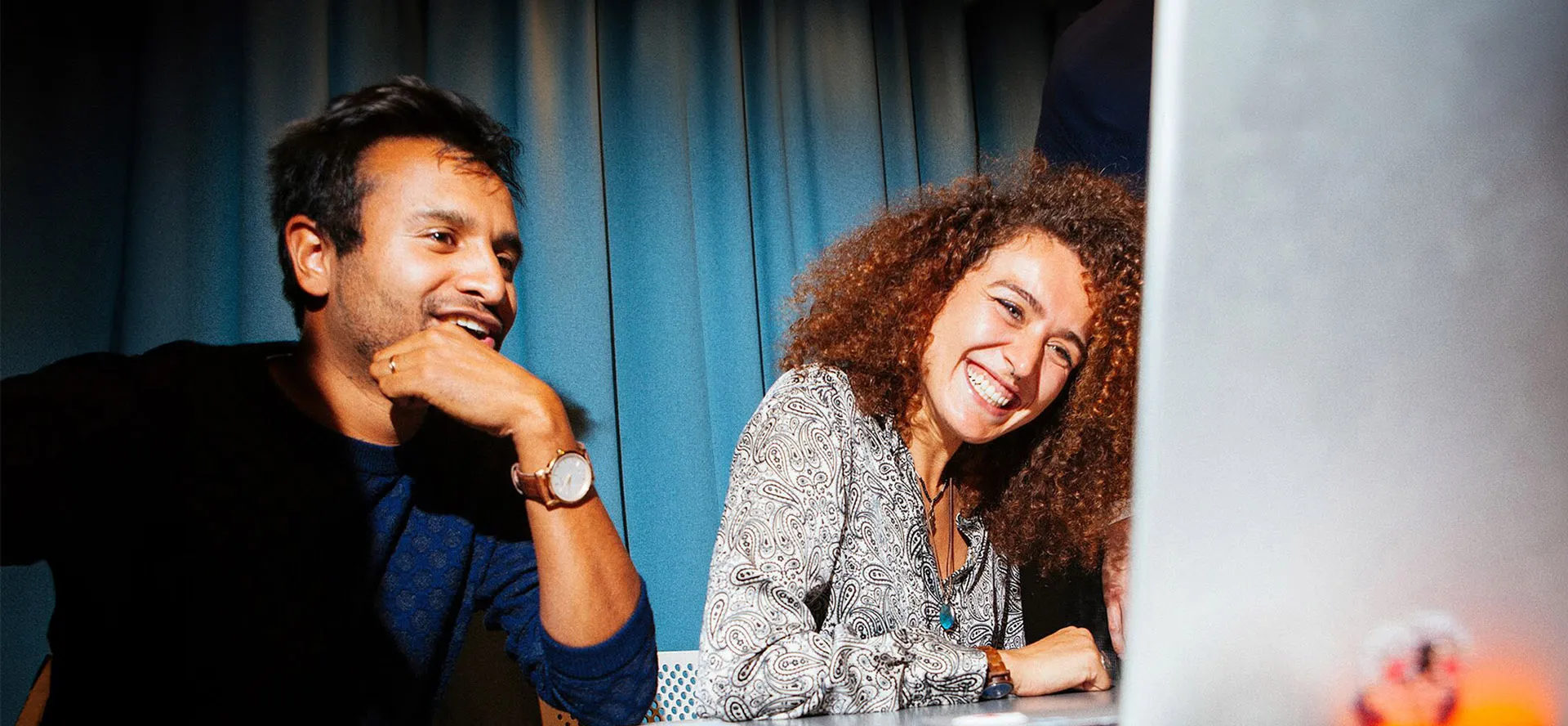 Two people smiling as they look at a laptop screen